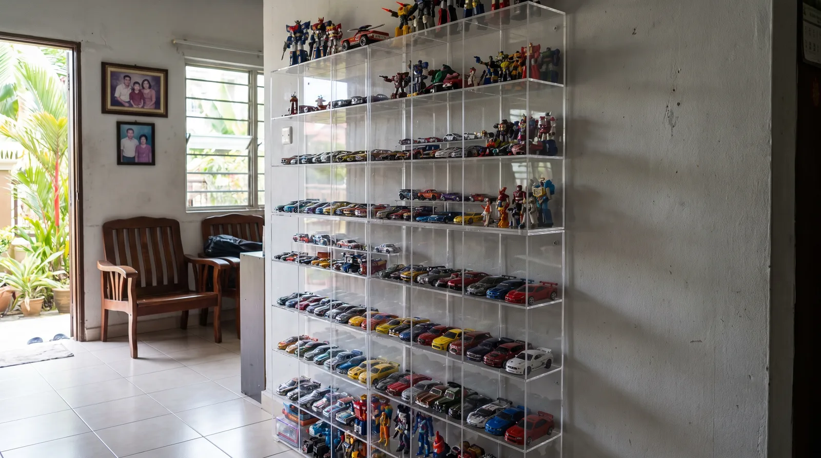 tall multi-tier acrylic display cabinet against a wall in a Malaysian home, filled with model cars and figures