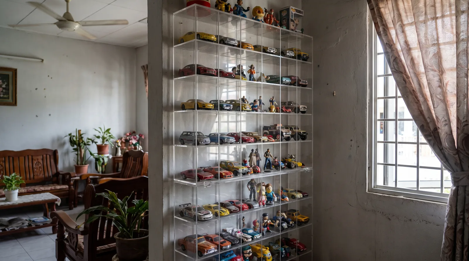 tall multi-tier acrylic display cabinet against a wall in a Malaysian home, filled with model cars and figures