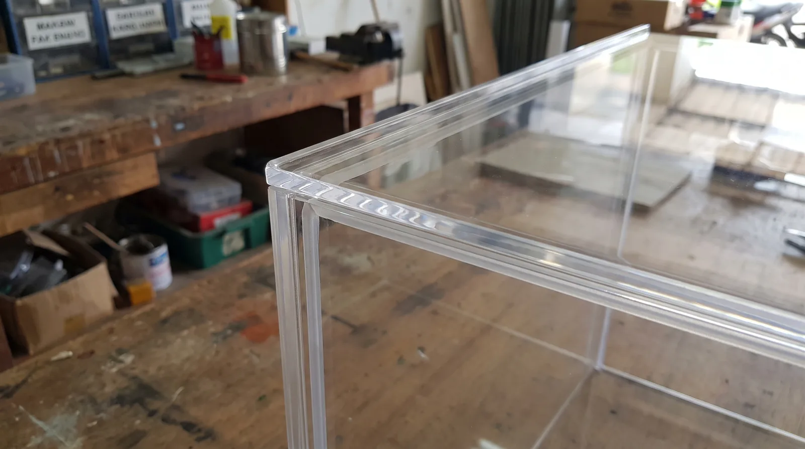 close-up of an acrylic display case corner joint, showing the clean polished edge and dust seal