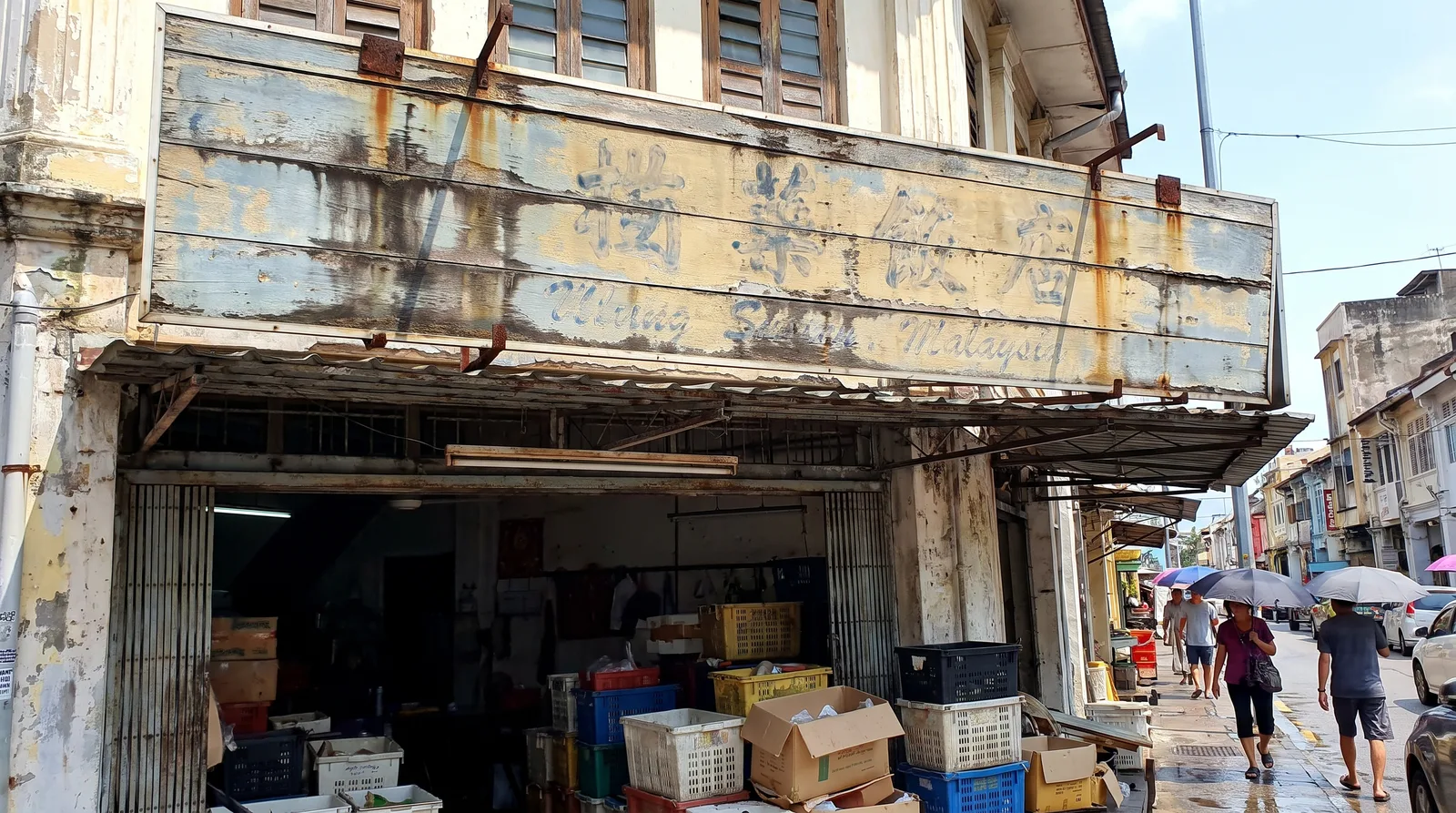 weathered outdoor business signboard on a Malaysian shopfront showing sun fading and rain streaks after years of tropica