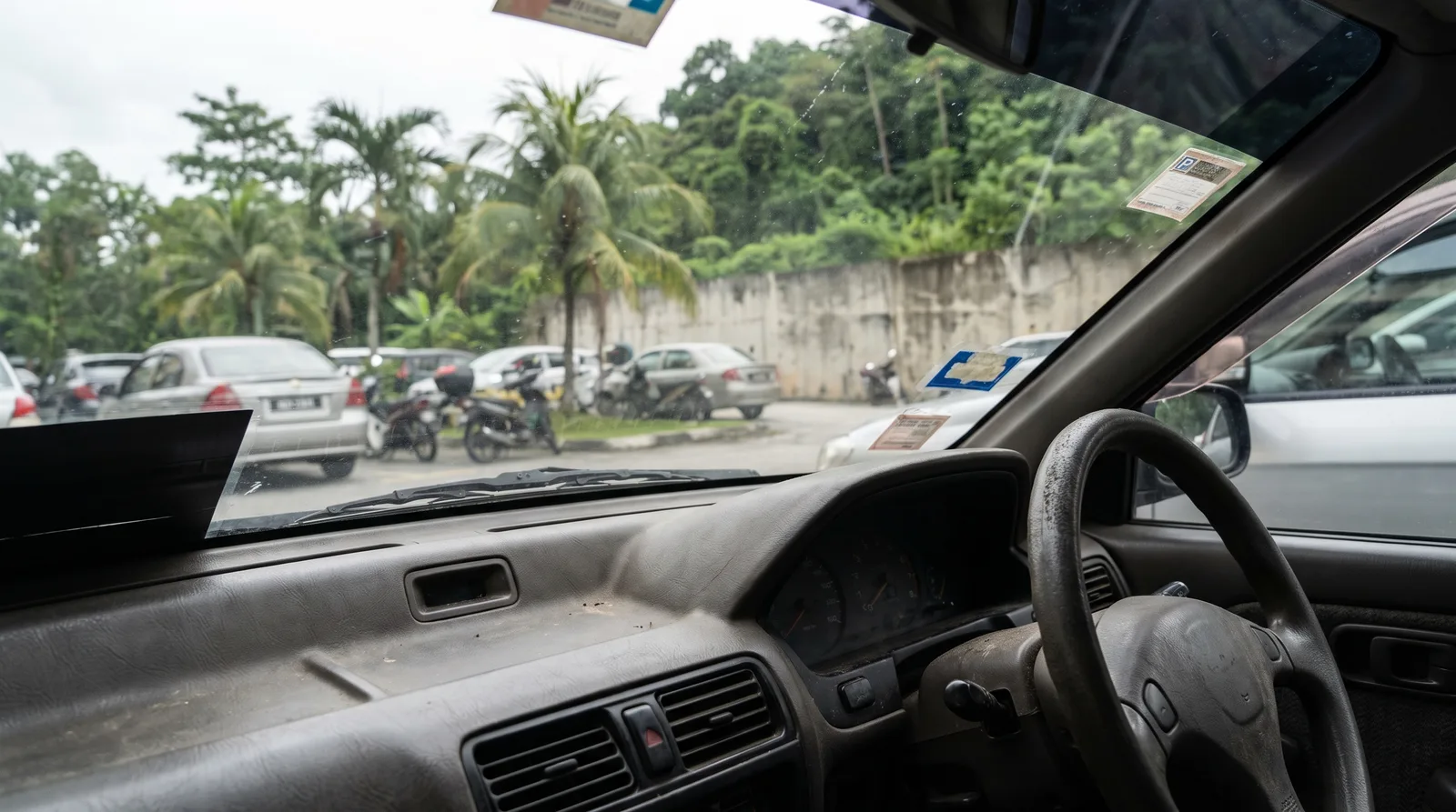 dashboard and windscreen of a car parked in a Malaysian carpark, seen from the drivers seat