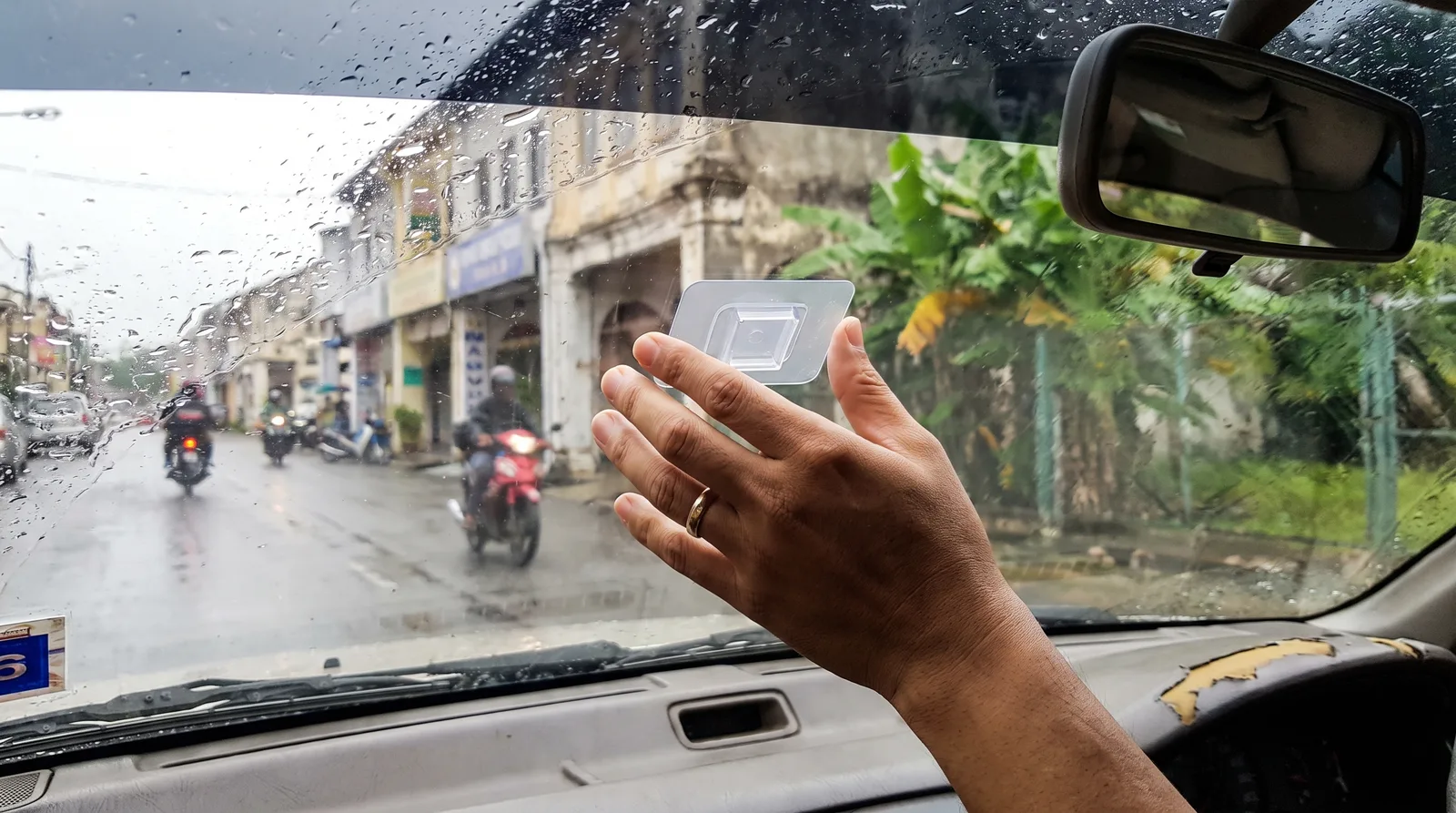 hand pressing an adhesive holder onto the inside of a car windscreen