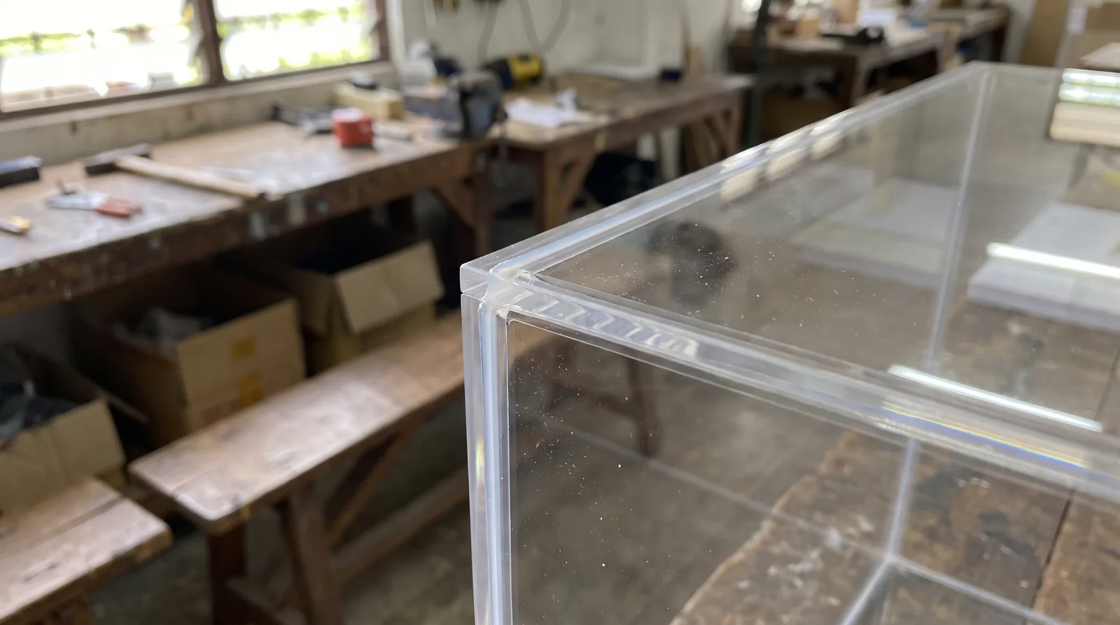 close-up of an acrylic display case corner joint, showing the clean polished edge and dust seal