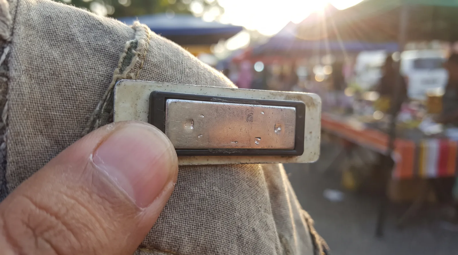close-up of the magnetic back fitting of a name badge held between finger and thumb
