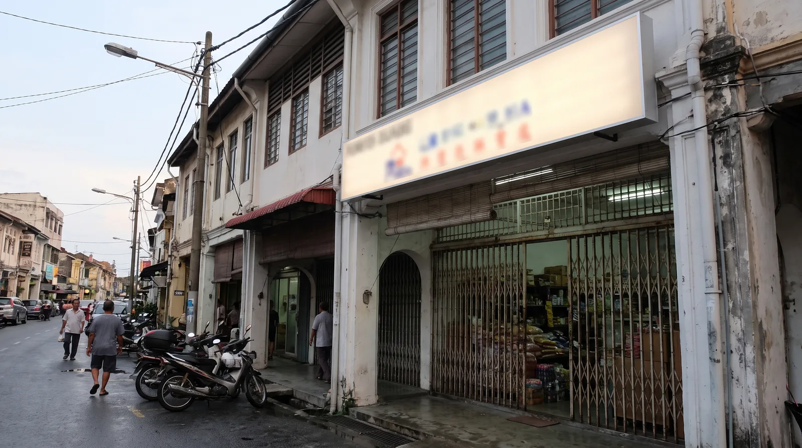 shopfront in a Malaysian town with a newly installed illuminated signboard, viewed from across the street