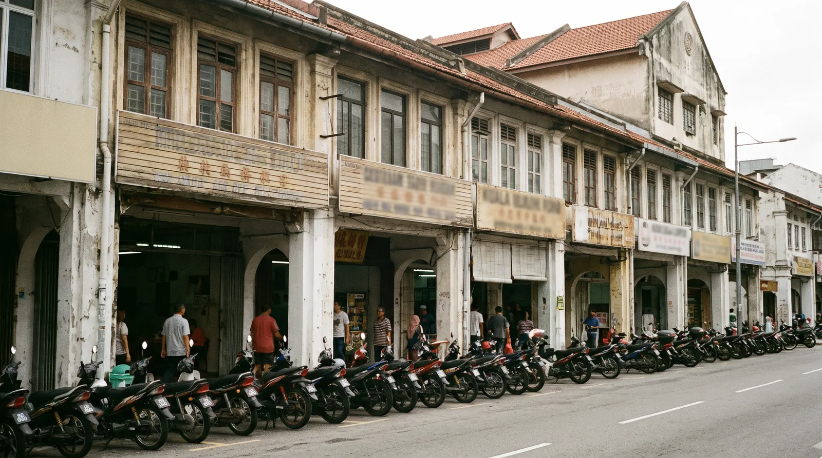 Row of Malaysian shophouses with horizontal fascia signboards above the five-foot way